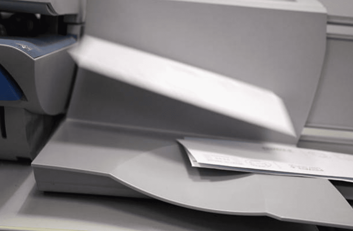 Printed envelopes flying out of a franking machine.